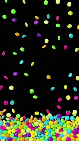 Loop animation of colorful candy dragees falling down on black background