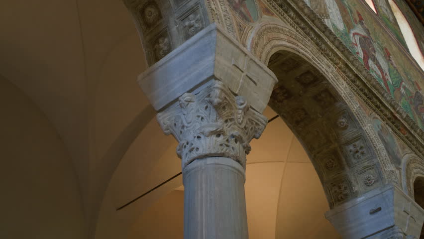 Handheld left-to-right shot of a white marble Corinthian column capital inside a church, highlighting intricate architectural detail.