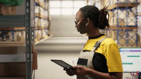 Black female industrial clerk working on order processing tasks with tablet, distribution center ensures efficient warehousing operation. Managing parcels data for e-commerce delivery. Camera B. - Powered by Shutterstock - Get 15% off with code: PIKWIZARD15