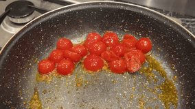 Top view of cherry tomatoes with garlic and herbs sautéing in a hot pan - Powered by Shutterstock - Get 15% off with code: PIKWIZARD15