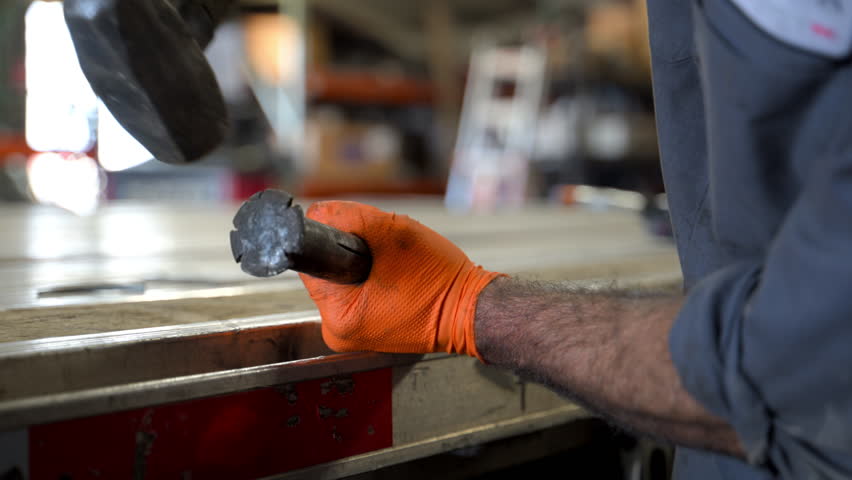 Welder at work, wearing protective gear, welding helmet and heavy-duty cloth. blue and orange sparks are flying as welding torch fuses metal together. Trailer repair
