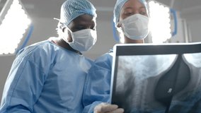 african american male and female surgeons looking at x-ray scans in operating theatre, slow motion 4k video - Powered by Shutterstock - Get 15% off with code: PIKWIZARD15