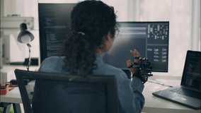 Female engineer uses a robotic glove controller while coding on a computer, testing circuit board technology, robotics, and artificial intelligence in a modern office workspace. - Powered by Shutterstock - Get 15% off with code: PIKWIZARD15