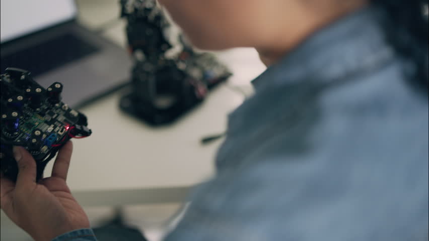 Close-up of a female engineer holding a robotic hand prototype with electronic circuits and LED lights, symbolizing artificial intelligence, robotics, and innovation in technology.