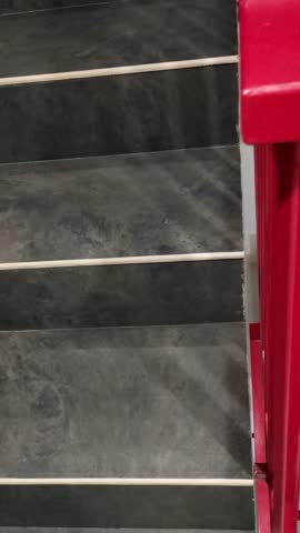 This video captures the essence of vertical movement with a striking focus on the red railing. A man is playing on his phone on the stairs while taking a break