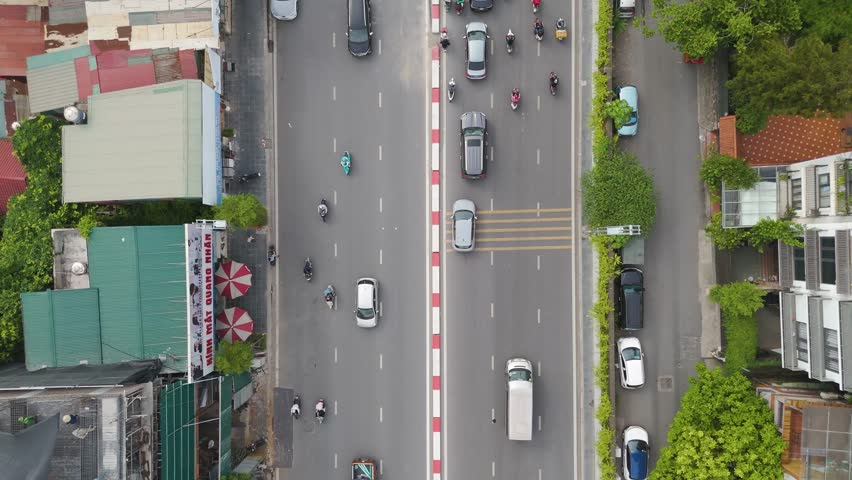 Rising top-down drone shot of a bustling urban intersection in Hanoi, Vietnam. The dense network of streets and buildings with vehicles moving through the traffic. UHD.