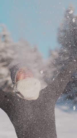 SLOW MOTION TIME WARP, CLOSE UP, DOF: Young woman is having fun in the snowy countryside playing with snow. Joyful female tourist throws a handful of fresh snow in the air on a sunny winter day.