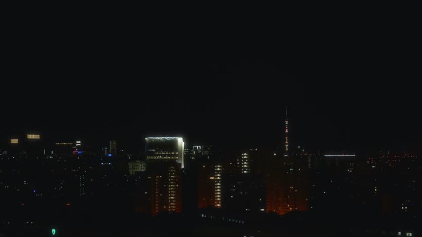 A static horizontal video of Moscow at night filmed from a skyscraper rooftop. The illuminated Ostankino Tower and city skyline stand out against the dark sky. High quality 4k footage