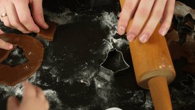 Mom flattening gingerbread dough with hand, next to wooden rolling pin and star shaped cookie cutter, making Christmas cookies with her child - Powered by Shutterstock - Get 15% off with code: PIKWIZARD15