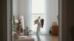 Smiling mother lifts her two year old toddler high into the air while playing together in a bright living room. Joyful parenting, laughter, and tender family bonding moment. High quality 4k footage - Powered by Shutterstock - Get 15% off with code: PIKWIZARD15