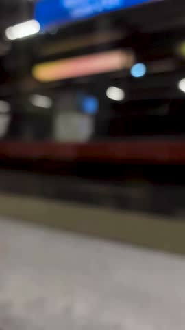Blurred view of a train station platform at night in Paris, featuring motion blur, lights, and signage.
