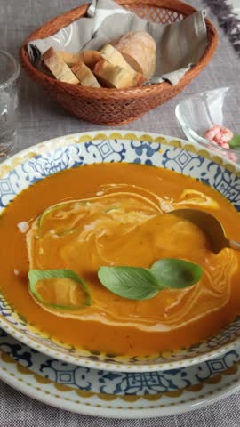 Anonymous eat pumpkin soup with basil and shrimp from blue patterned porcelain plate. Homemade healthy food. Farm products.
