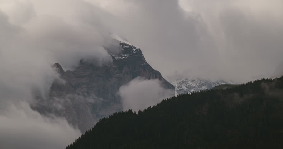 Timelapse close up of the majestic Eiger peak in Switzerland, partially covered in snow and surrounded by dramatic moving clouds