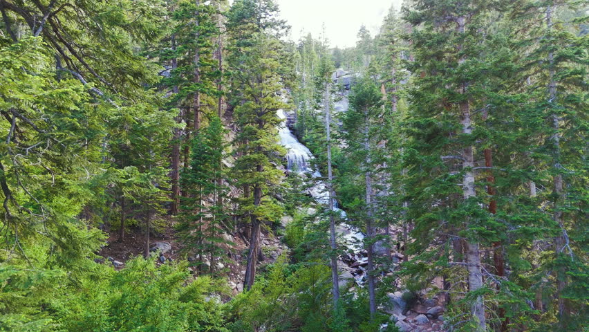 Cinematic aerial shot of cascading waterfalls in Sierra Nevada Mountains, California, USA