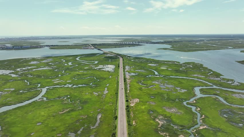 Intersection road of New Jersey between green marshland and wetland with bridges between islands. Sunny summer day in stone harbor city with atlantic Ocean in distance.