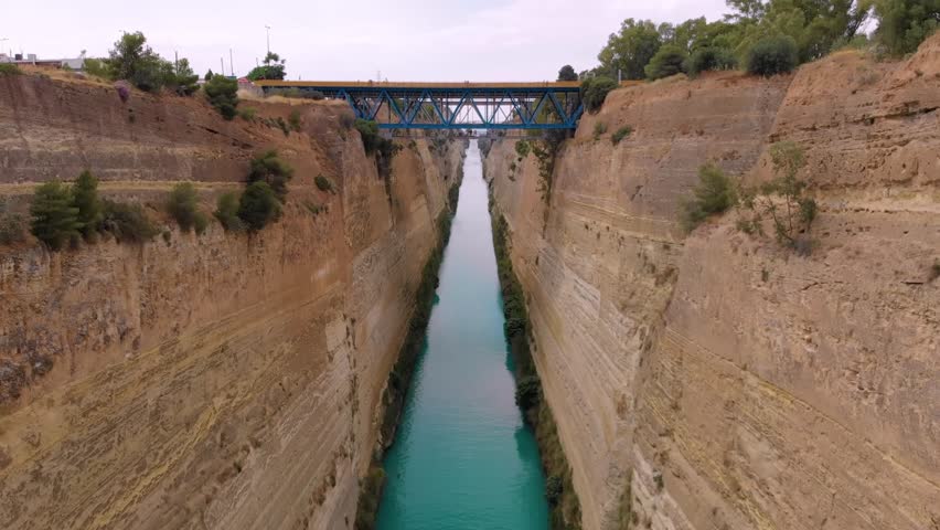 aerial drone footage captures the impressive Corinth Canal in Greece, showcasing its narrow passage cutting through the Isthmus of Corinth, connecting the Gulf of Corinth with the Saronic Gulf.