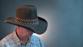 Closeup portrait of a cowboy senior man with his hat in a vintage Harcourt style lighting - Powered by Shutterstock - Get 15% off with code: PIKWIZARD15