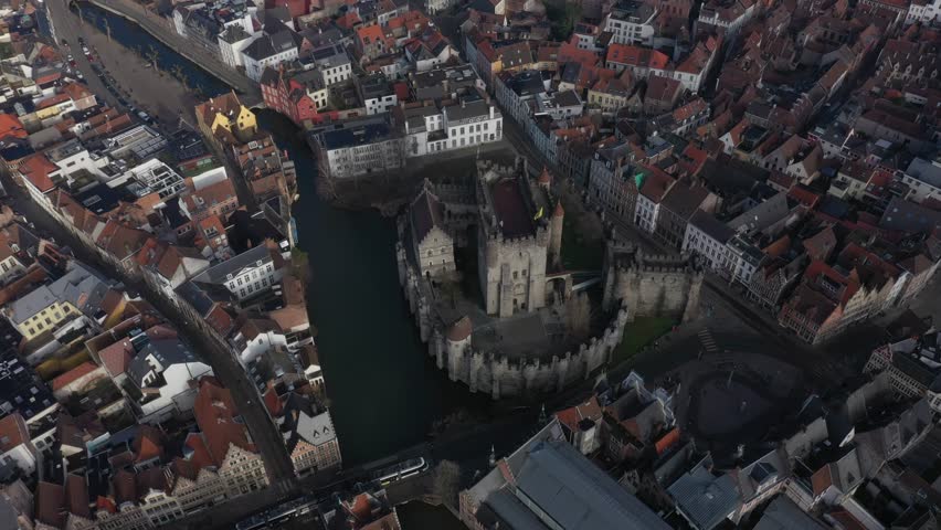 Aerial view of the medieval Gravensteen Castle surrounded by a moat and buildings with red roofs, Ghent, Flanders, Belgium.