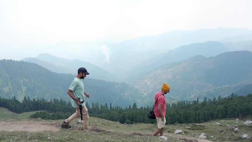 Two men walking, chatting, and enjoying the sunset outdoors at the top of Raghupur Fort, Tirthan Valley, Himachal Pradesh, India.