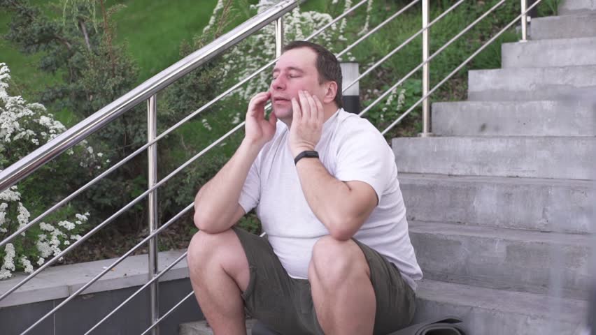 A fat man sits on the stairs and is sad about not being able to lose weight