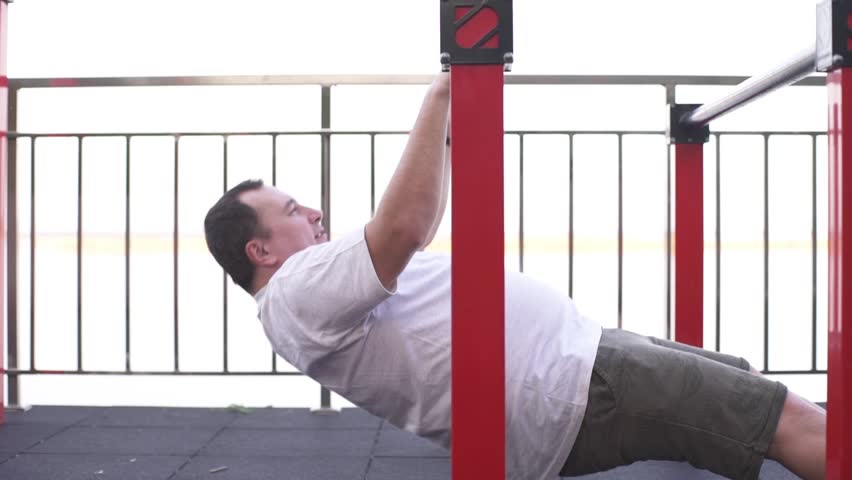 Fat man doing gymnastics to lose weight on the sports ground