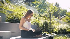 Backlit portrait of a blond caucasian woman sitting outdoor on public steps surrounded by greenery and working remotely on notebook. Urban lifestyle of a freelancer. Negative space. - Powered by Shutterstock - Get 15% off with code: PIKWIZARD15