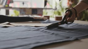 Close-up of hand of unrecognizable young female tailor carefully cutting black fabric with sharp scissors, with smooth precise movements, while working in couture fashion atelier - Powered by Shutterstock - Get 15% off with code: PIKWIZARD15