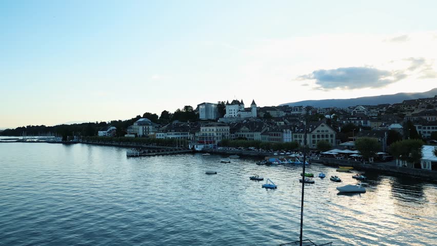 Aerial view of the historic Nyon Castle overlooking the serene waters of Lake Geneva with the city nestled along the shoreline, Nyon, Vaud, Switzerland.
