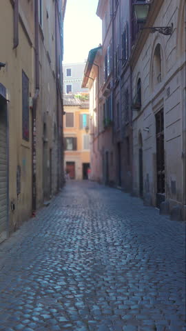 Narrow cobblestone street in historic European city with old stone buildings, shuttered windows, and atmospheric perspective of traditional architecture