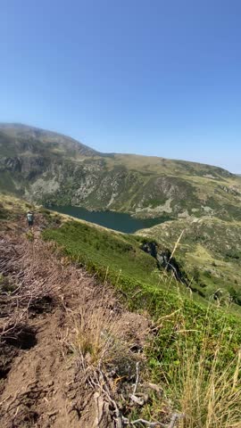 A static shot of the Artax pond in the Pyrenees. We see a hiker walking from behind.
Summer 2025