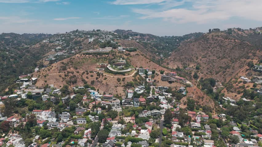 Wide descending and panning aerial shot of upscale hillside homes in Hollywood Hills, California. 4K