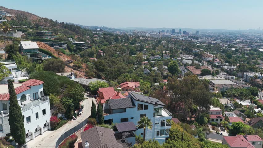 Rising aerial panning shot of wealthy homes on the hills above Hollywood in Los Angeles, California. 4K