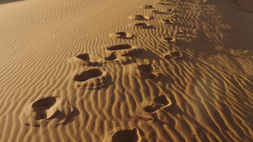Footprints in the sand dunes of the Sahara Desert. A journey through the vast expanse of the desert. The sun setting over the horizon. A sense of adventure and exploration.