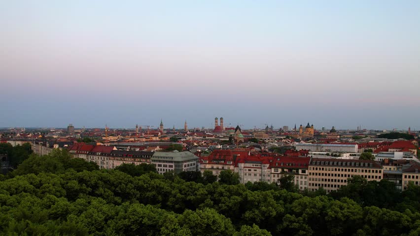 4K Aerial Drone video of a quiet early morning in Munich city center overlooking St Lukas church, Isar river, Marienplatz and the Angel of Peace Friedensengel. Beautiful skyline at a purple sunrise