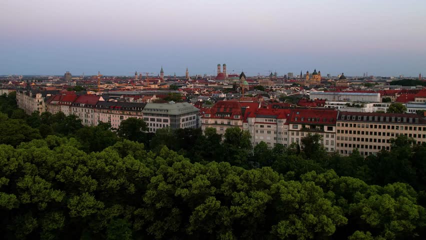 4K Aerial Drone video of a quiet early morning in Munich city center overlooking St Lukas church, Isar river, Marienplatz and the Angel of Peace Friedensengel. Beautiful skyline at a purple sunrise