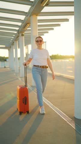 Woman confidently pulling a suitcase in an airport terminal. Slow motion