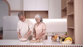 An older Asian couple preparing dough in a modern kitchen. They share a happy domestic moment showing active healthy retired life. - Powered by Shutterstock - Get 15% off with code: PIKWIZARD15