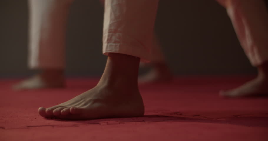 Bare feet of karateka train kick on mat of martial arts club