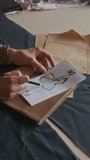 Vertical close-up of hands of two anonymous female fashion designers drawing sketch of dress, discussing style, while creating new collection of trendy clothes in workshop - Powered by Shutterstock - Get 15% off with code: PIKWIZARD15