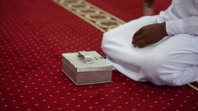 A man puts money into a mosque's donation box. - Powered by Shutterstock - Get 15% off with code: PIKWIZARD15