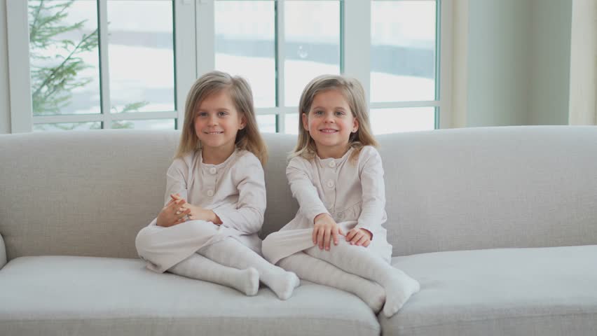 Happy family sisterly love. Two funny little twin sisters girls smiling playing together at home indoors. Happy children lifestyle. Identical twin girls. Girls friendship and youth