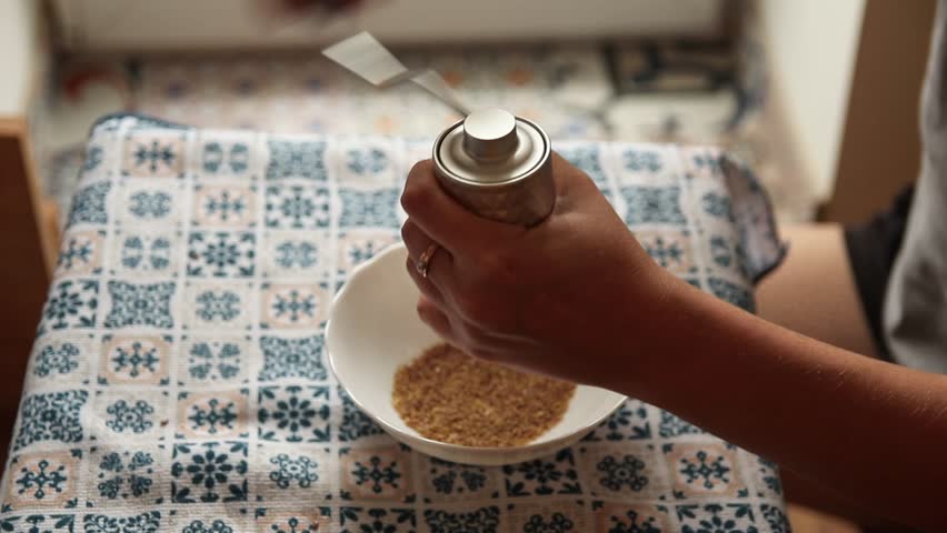 A Woman Manually Grinding Flax Seeds for Omega-3. Healthy Lifestyle. A Woman Grinding Flax Seeds at Home. Simple and Natural.