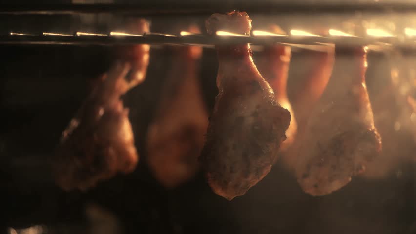 Juicy chicken drumsticks roasting on an oven rack, with golden baked potatoes beneath. Perfectly cooked meal showcasing a delicious combination of flavors and textures