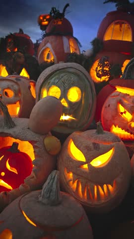 Glowing carved pumpkins with spooky faces lit by candles at night. Traditional jack o lantern display for Halloween holiday, seasonal decoration at the annual Halloween Fair.