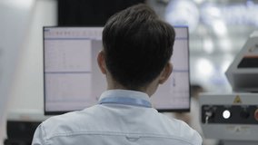 Back view of male engineer analyzing data on computer monitor in modern laboratory. Software development, digital programming, coding and industrial technology research environment. - Powered by Shutterstock - Get 15% off with code: PIKWIZARD15