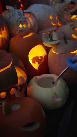 Glowing carved pumpkins with spooky faces lit by candles at night. Traditional jack o lantern display for Halloween holiday, seasonal decoration at the annual Halloween Fair.