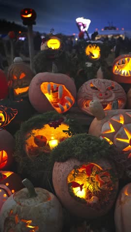 Glowing carved pumpkins with spooky faces lit by candles at night. Traditional jack o lantern display for Halloween holiday, seasonal decoration at the annual Halloween Fair.