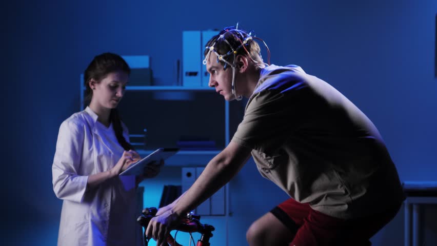 EEG topographer for examining brain, doctor making electrogram of scalp activity. Researching of brain work, man riding bicycle in electroencephalography headset. Rehabilitation after damage in sport.