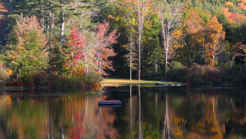 Scenic view of Ricker pond in Vermont with fall foliage with perfect reflection.