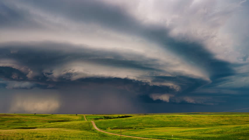 An incredible severe weather supercell thunderstorm cloud slowly approaches, showcasing its massive rotating structure and the looming power of an intense atmospheric event